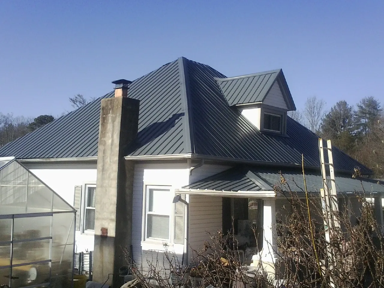 Dark blue standing seam metal roof on a white farmhouse with dormer — Slate & Tile Roof Repair by Roofing Brothers in Sherrodsville