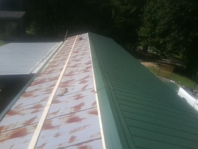 Old rusted panels beside newly installed green metal roofing — Wind Damage Roof Repair by Roofing Brothers in Sherrodsville