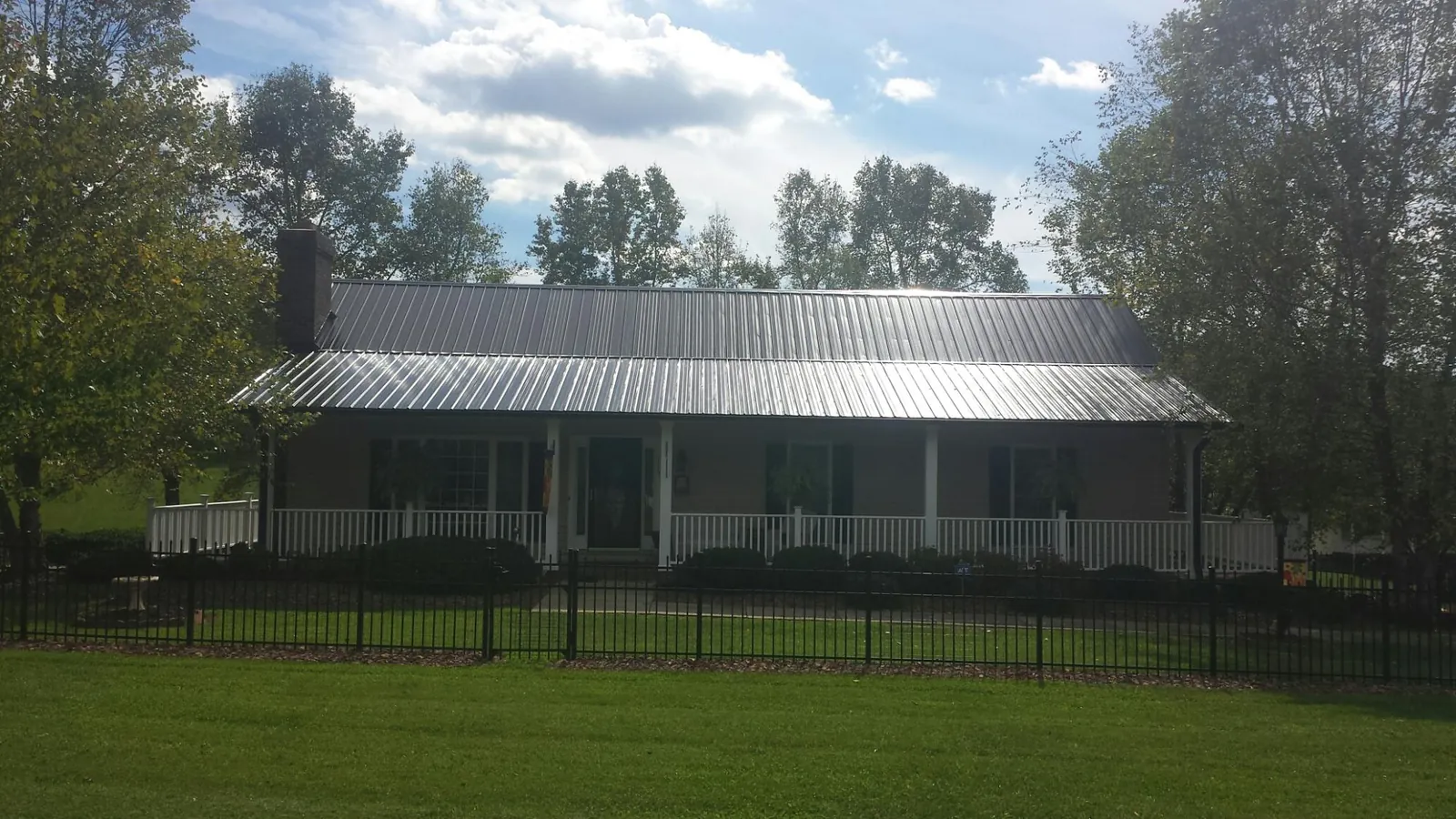 Gray metal roof on a brick ranch with a full width front porch — Gutter Guard Installation work by our crew in Sherrodsville