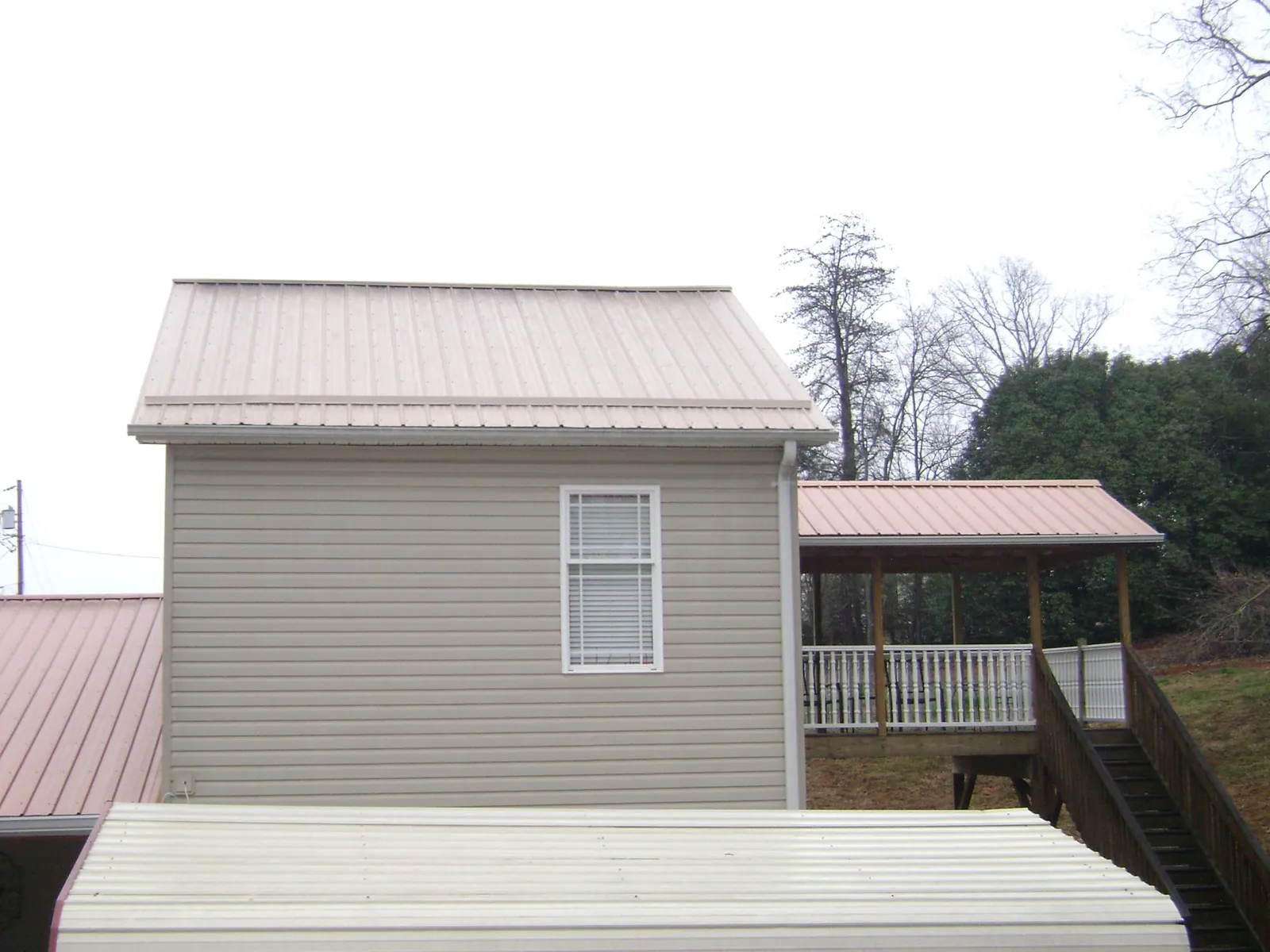 Tan metal roofs on a two story addition and attached porch, from a Roof Replacement job in Sherrodsville