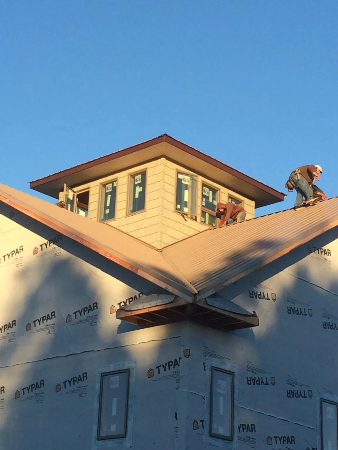Roofers working around a rooftop cupola on a new metal roof at sunset — Roof Waterproofing in Sherrodsville by Roofing Brothers